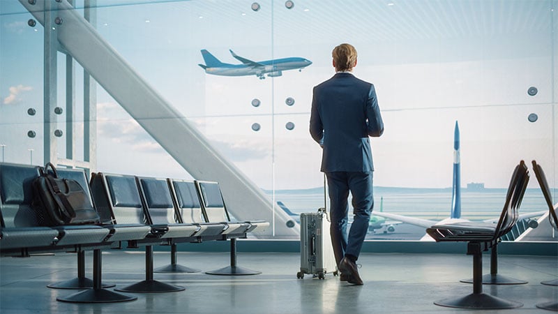 A man with a suitcase watches an airplane take off