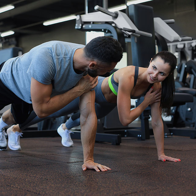Man and woman are standing in a plank in the gym