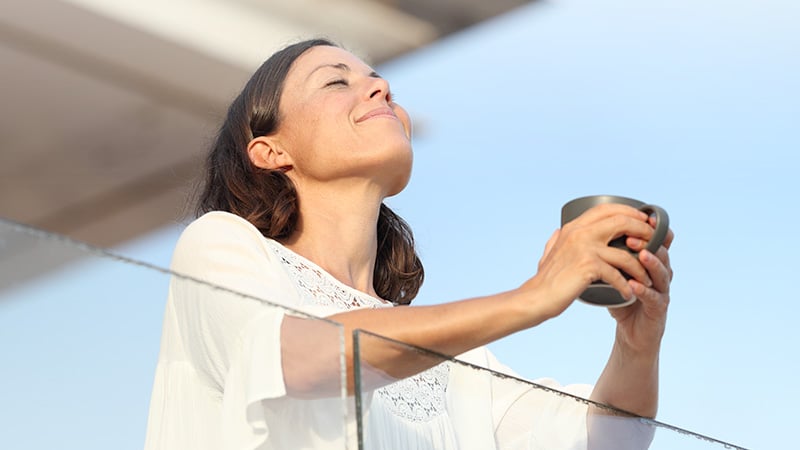 A woman on the glass balcony with a cup of drink