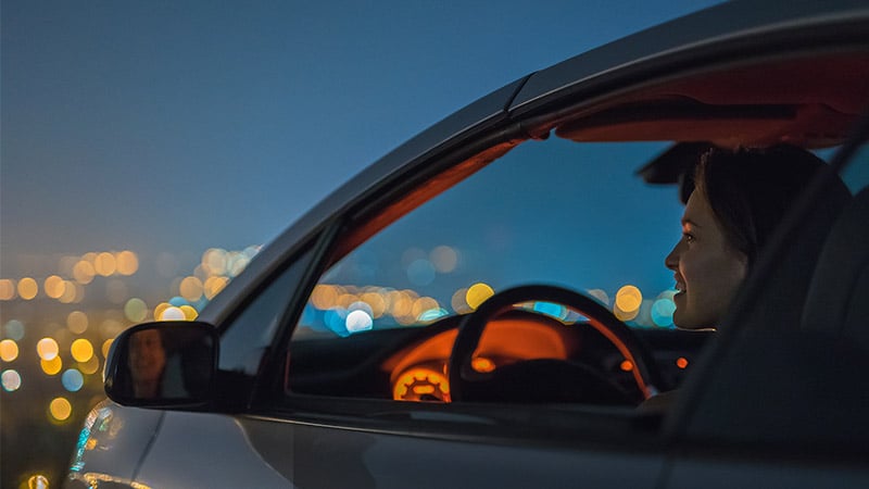 A woman sitting in the car and looking at the night city landscape